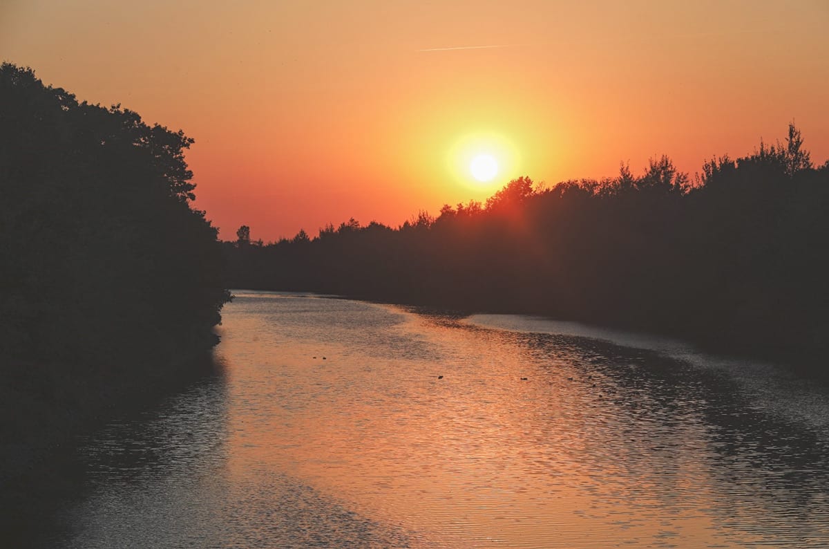 Landschaft mit Fluss bei Sonnenuntergang